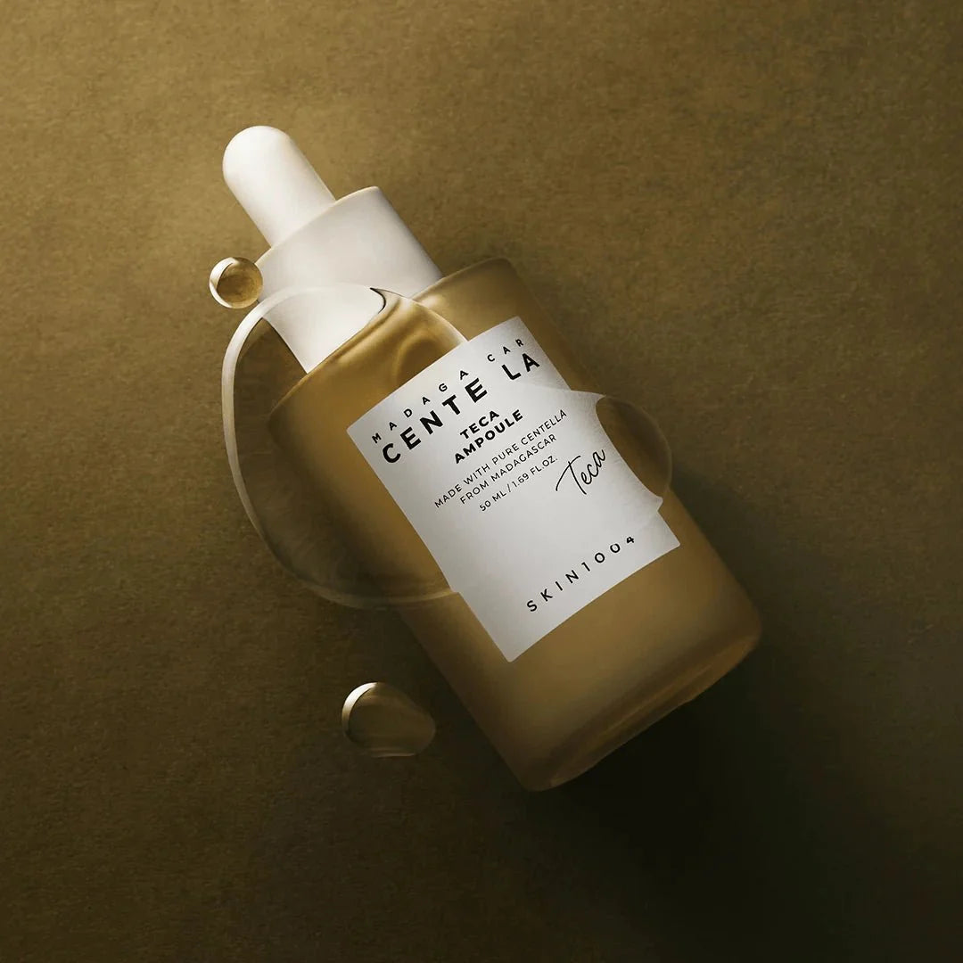 Artistic overhead view of the Skin1004 Teca Ampoule bottle surrounded by liquid droplets.