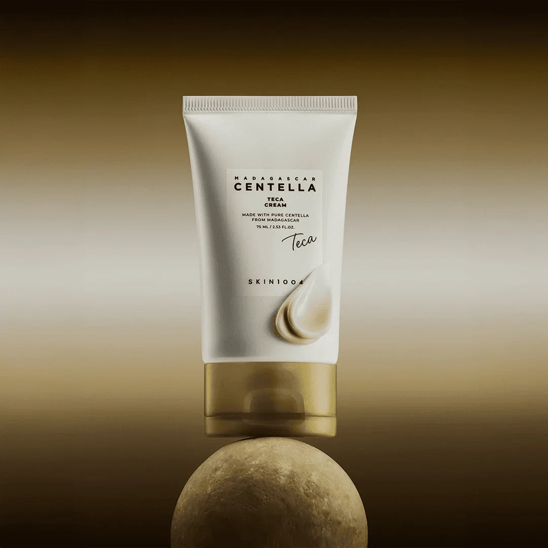 Skin1004 Madagascar Centella Teca Cream packaging balanced on a stone with a drop of white cream on the tube.